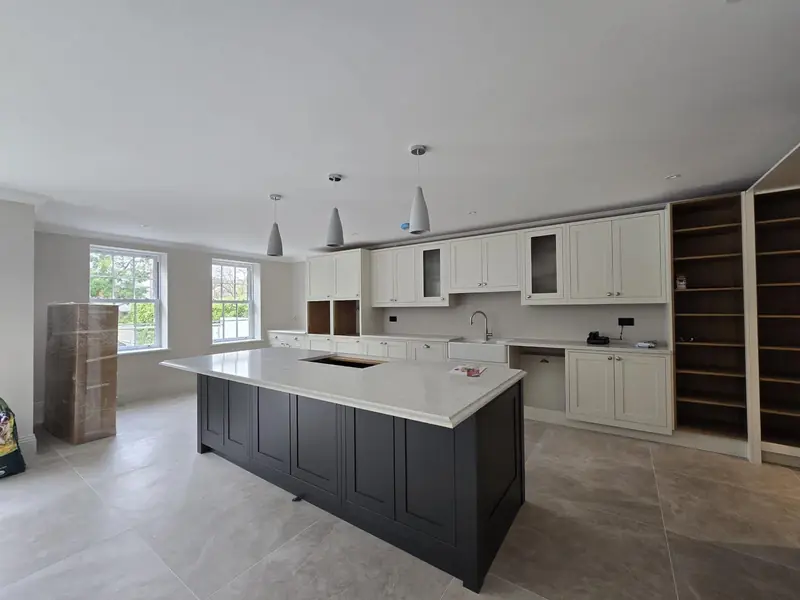 Shaker-style kitchen with a dark island, white quartz worktop and pendant lights
