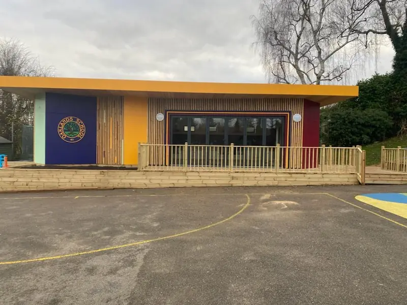 Single-storey modular classroom with timber cladding, a deck and a ramp at Oaklands School
